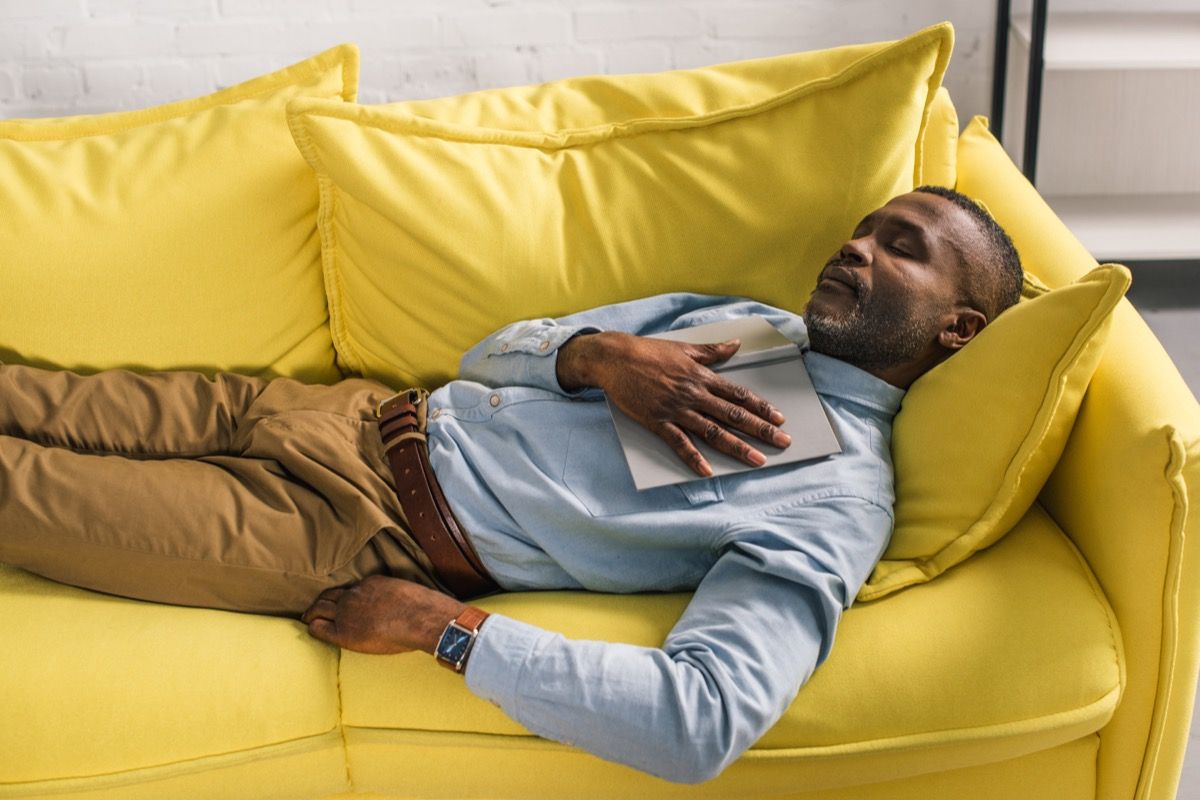 Alter schwarzer Mann in Khakis und Knopf unten Nickerchen auf gelber Couch