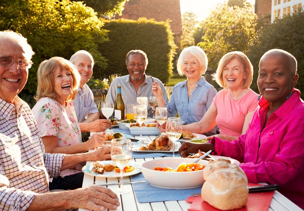 възрастни хора от бели и черни раси споделят вечеря на открито