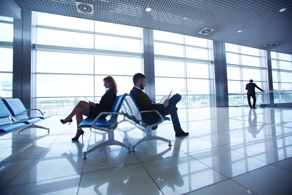 du žmonės sėdi tuščiame oro uoste