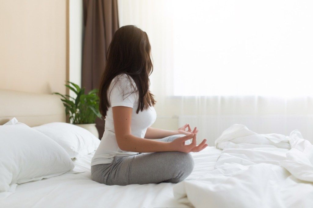 Kvinne som mediterer i sengen {Spiritual}