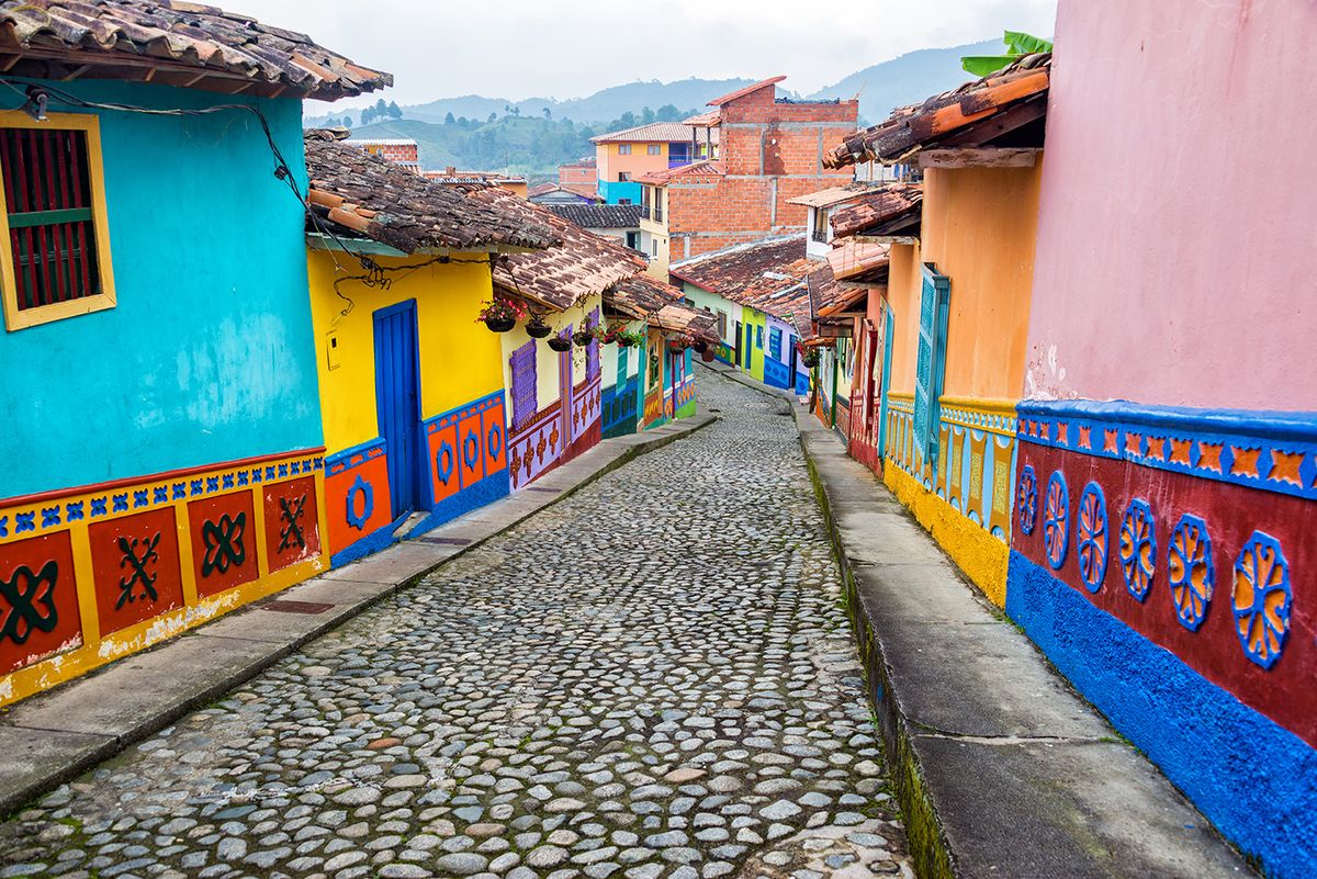 บ้านโคโลเนียลสีสันสดใสบนถนนที่ปูด้วยหินใน Guatape, Antioquia ในโคลอมเบีย
