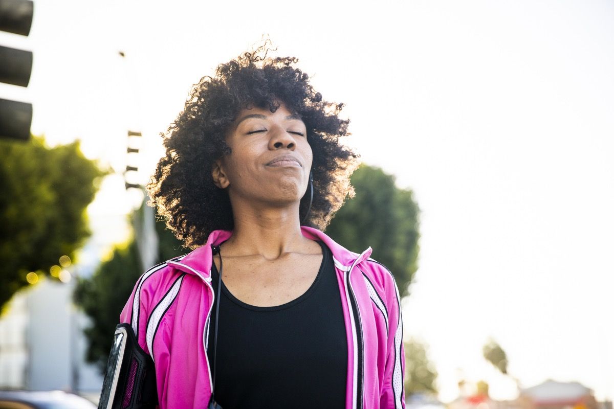 Mujer negra respira profundo al aire libre, hábitos después de los 40