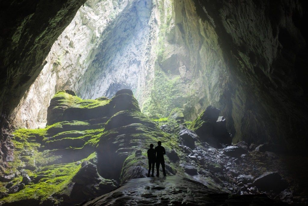 एक विशाल गुफा में खड़े दो लोगों की पीठ