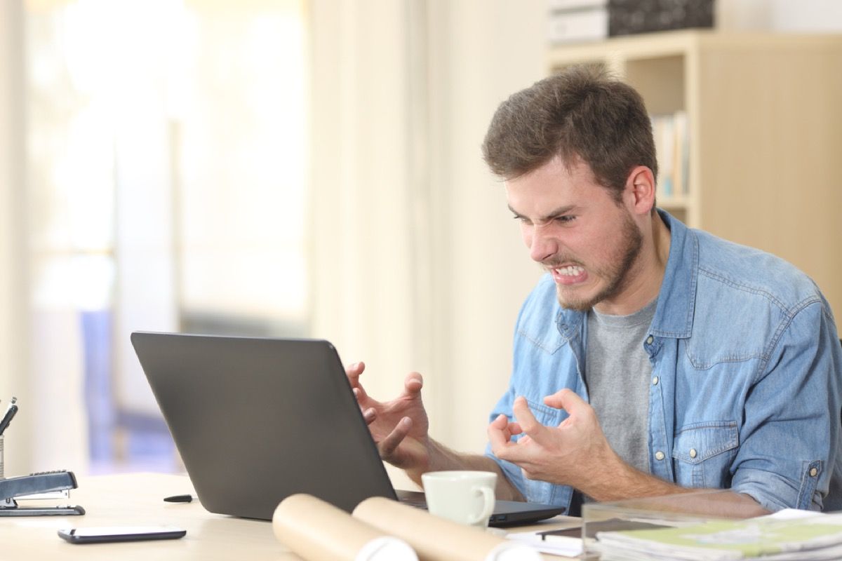 hombre blanco enojado gritando a la computadora portátil