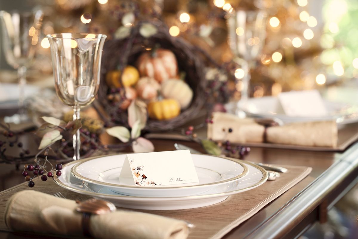Efterårsferie Thanksgiving-spisning med stedkort og traditionelt centerpiece fyldt med græskar og kalebasser.