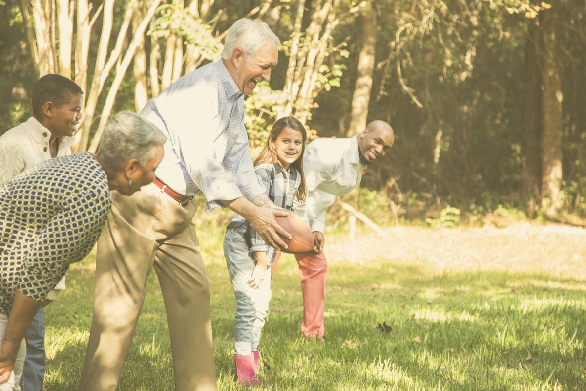 Familiari multietnici e multigenerazionali che giocano insieme ai nonni a una partita di calcio