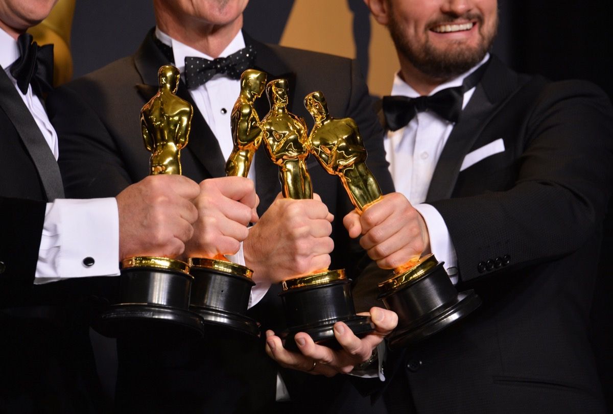 muži držiaci sochy Oscarov