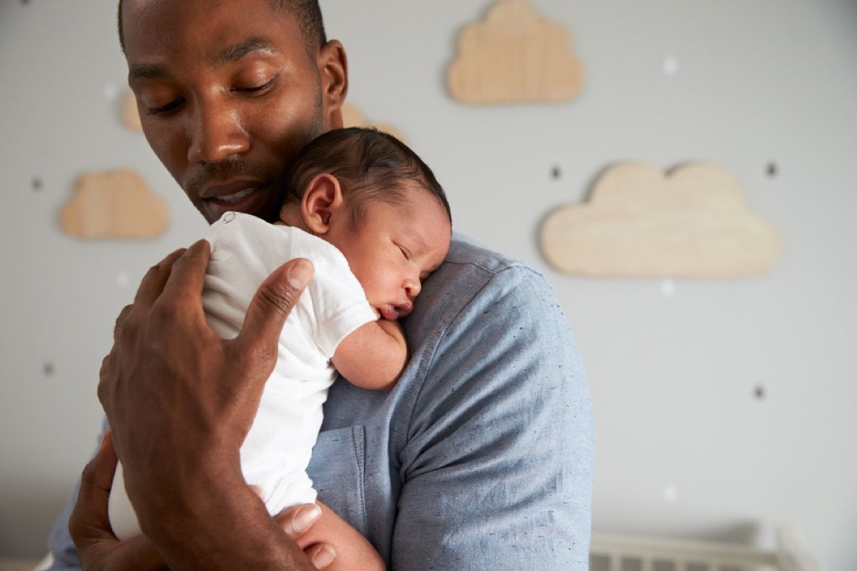 svart far som holder nyfødt baby på brystet