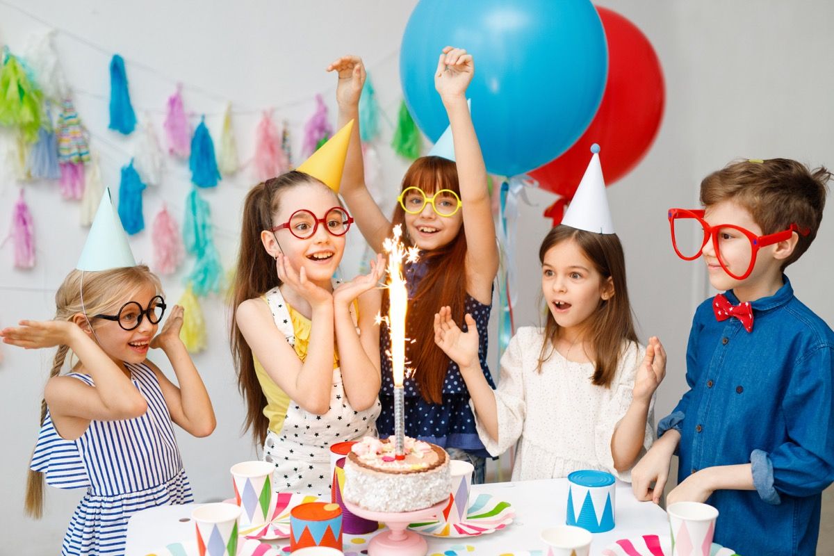 cinci copii în jurul unui tort de ziua de naștere