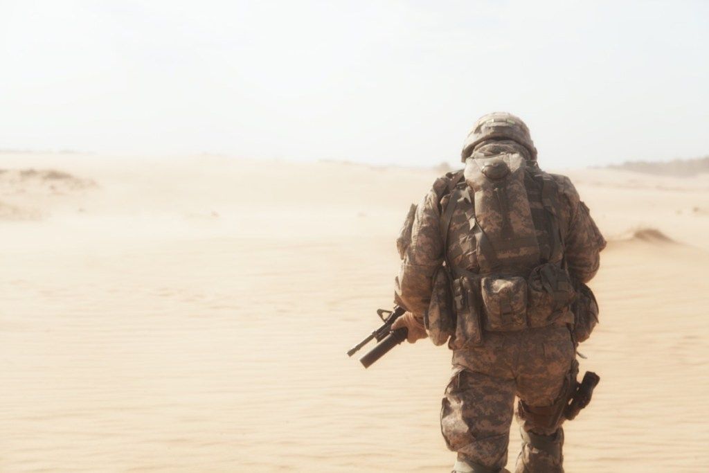 militārs cilvēks no aizmugures dodas tuksnesī