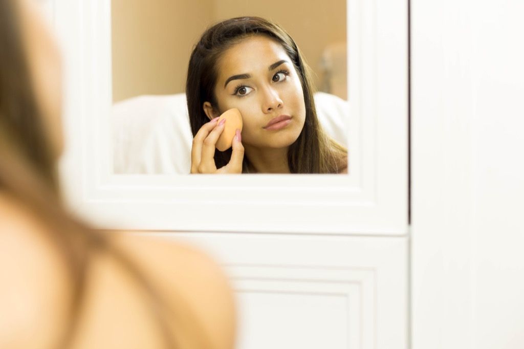 鏡に化粧をしている女性
