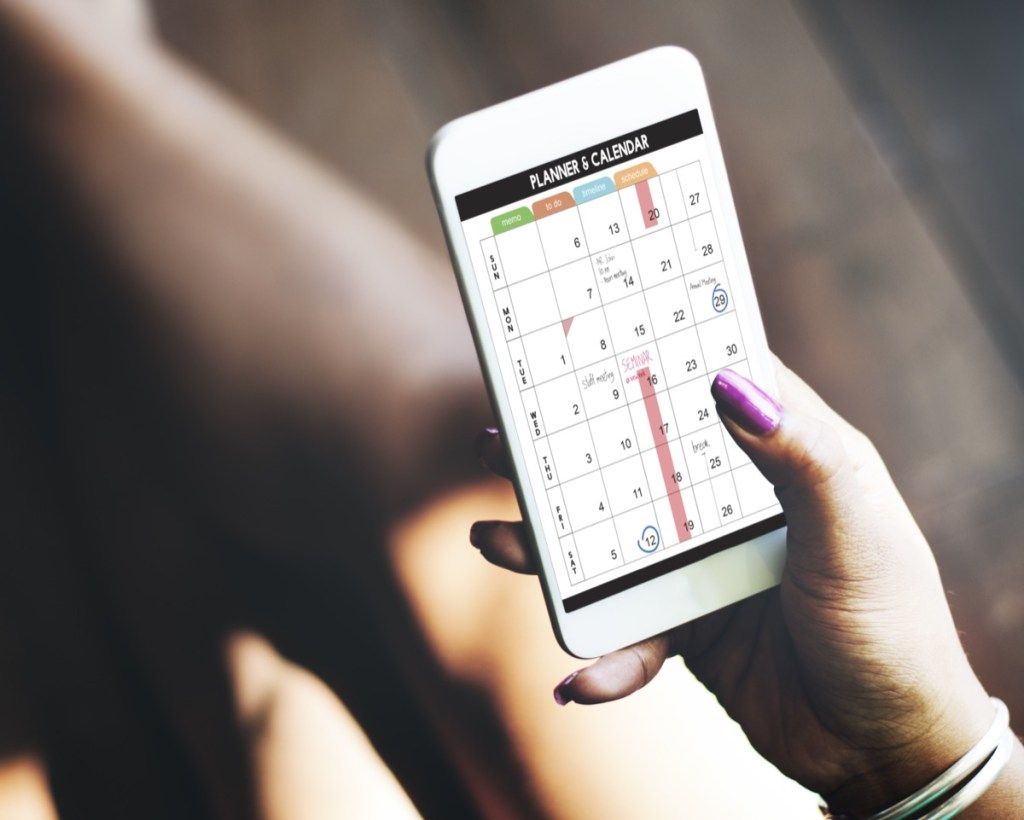Nainen käyttää kalenteria älypuhelimellaan