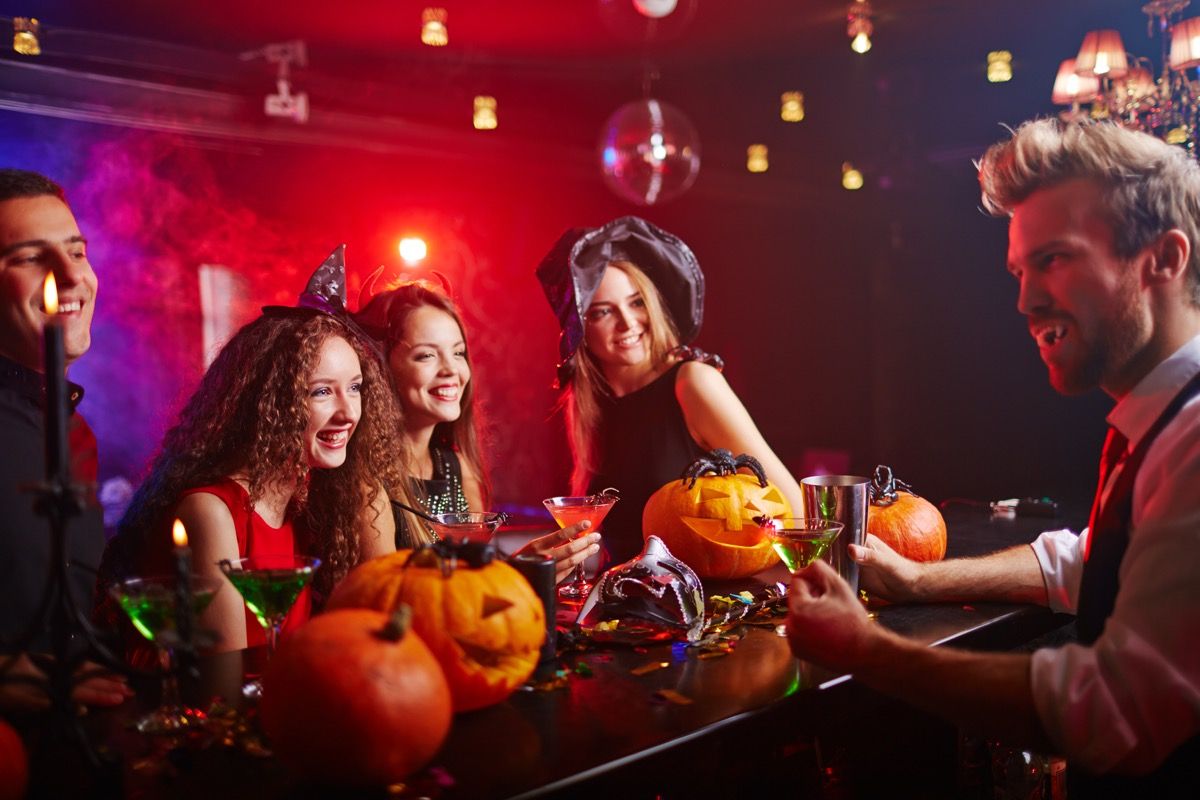 ľudia sediaci pri bare v halloweenských kostýmoch, ktoré majú zahodiť