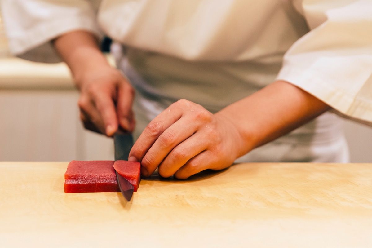 Mann schneidet Thunfischsteak mit Messer