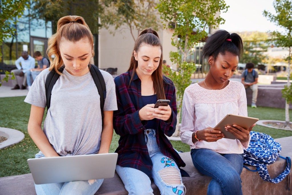 Группа девочек-подростков, использующих свои электронные устройства Как изменилось воспитание детей
