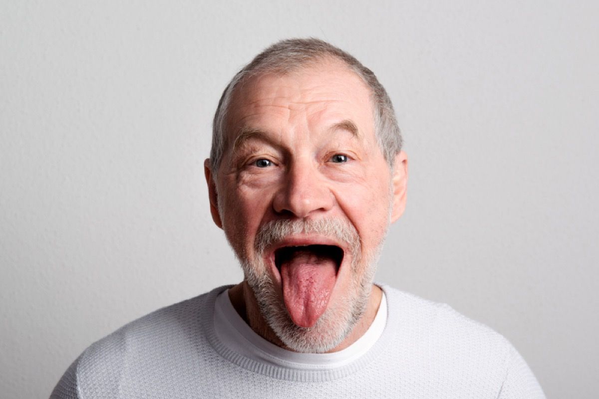 Hombre blanco mayor mirando a la cámara y sacando la lengua