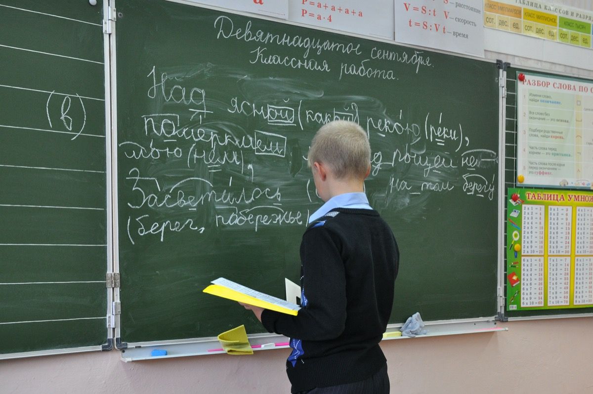 چھوٹا لڑکا بلیک بورڈ پر روسی لکھ رہا ہے