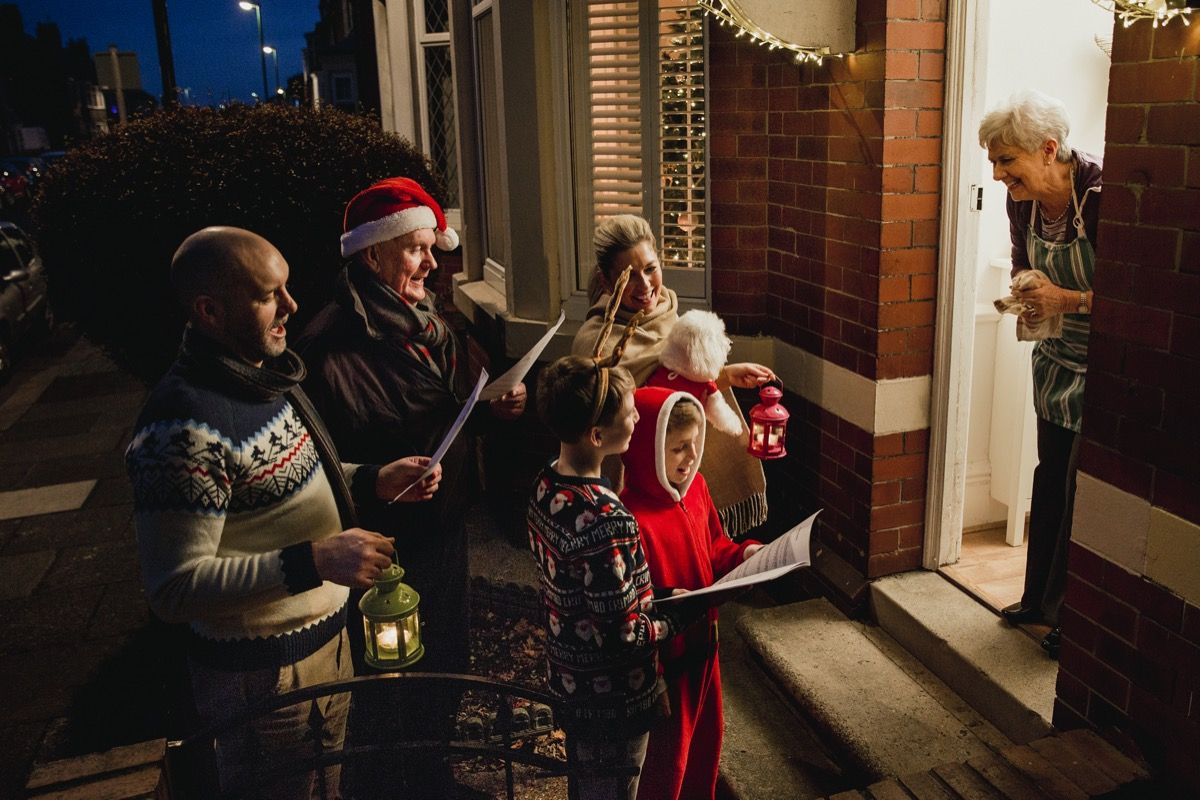 Parents, enfants et grand-père chantant des chants de Noël pour femme âgée