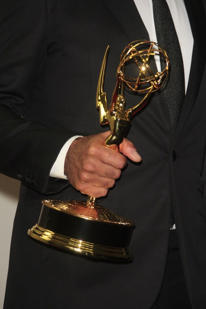 Tangan hitam memegang patung Emmy