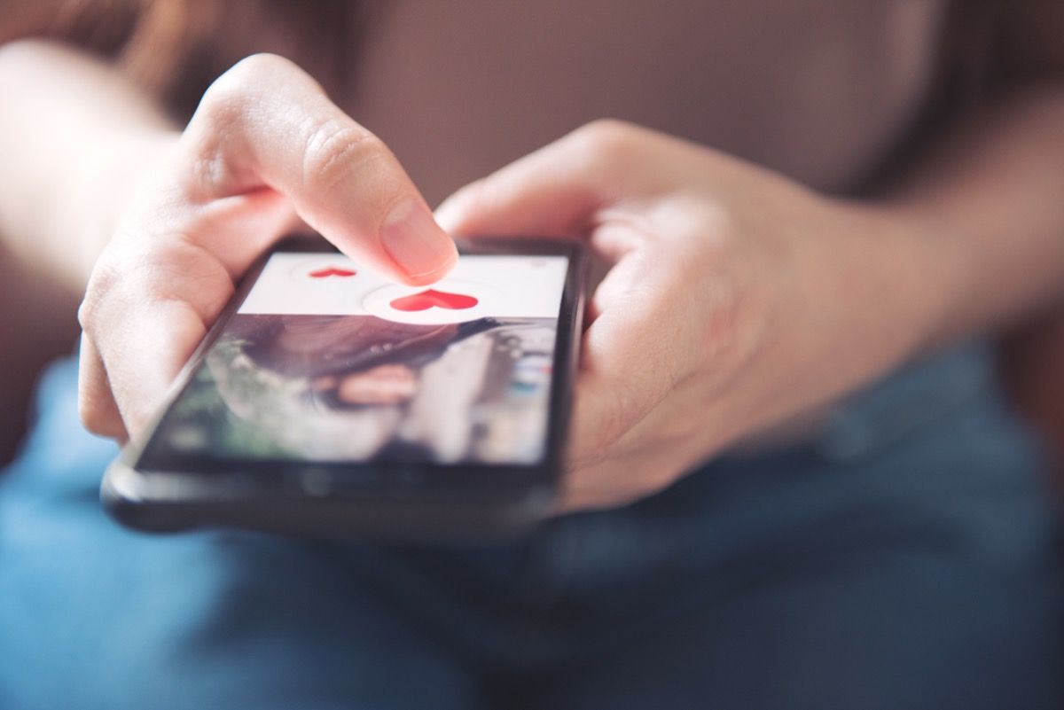 Finger der Frau, die Herzsymbol auf Bildschirm in der mobilen Smartphone-Anwendung drückt. Online-Dating-App, Valentinstag