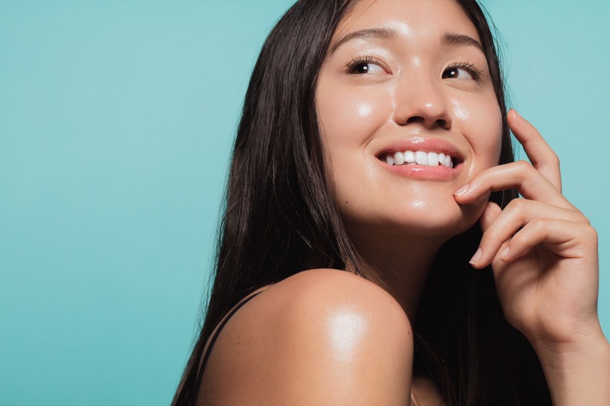 close-up de uma linda garota asiática com pele brilhante contra um fundo azul. Lindo rosto de menina com pele fresca e saudável.
