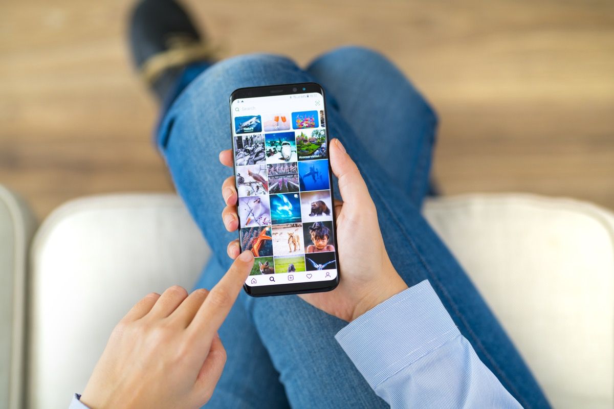 ผู้หญิงใช้สมาร์ทโฟนบนโซฟา สมาร์ทโฟนคือ iPhone 8 ที่แสดงแอปพลิเคชัน Instagram iPhone เป็นสมาร์ทโฟนหน้าจอสัมผัสที่พัฒนาโดย Apple Inc.