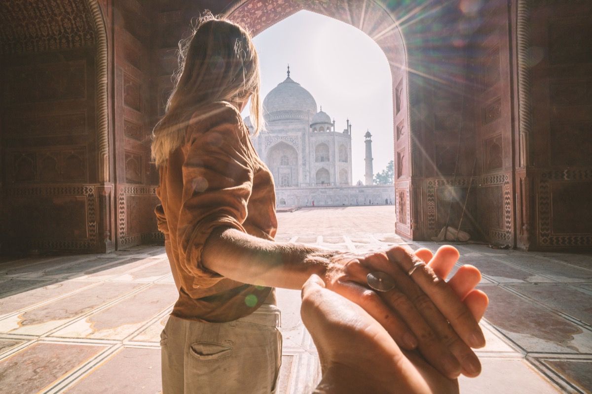 følg meg til Taj Mahal, India. Kvinnelig turist som fører kjæreste til det fantastiske berømte mausoleet i Agra. Folk reiser konsept