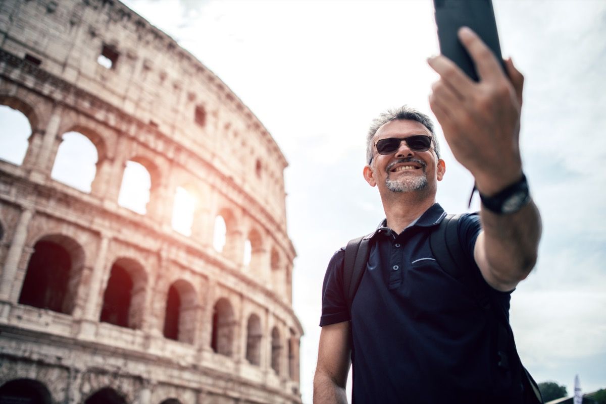midaldrende hvid mand tager en selfie foran colosseum