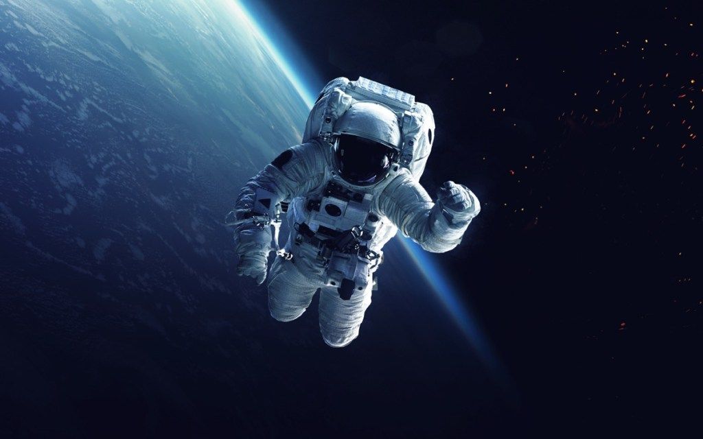 астронавт, работещ в космоса със земя на заден план