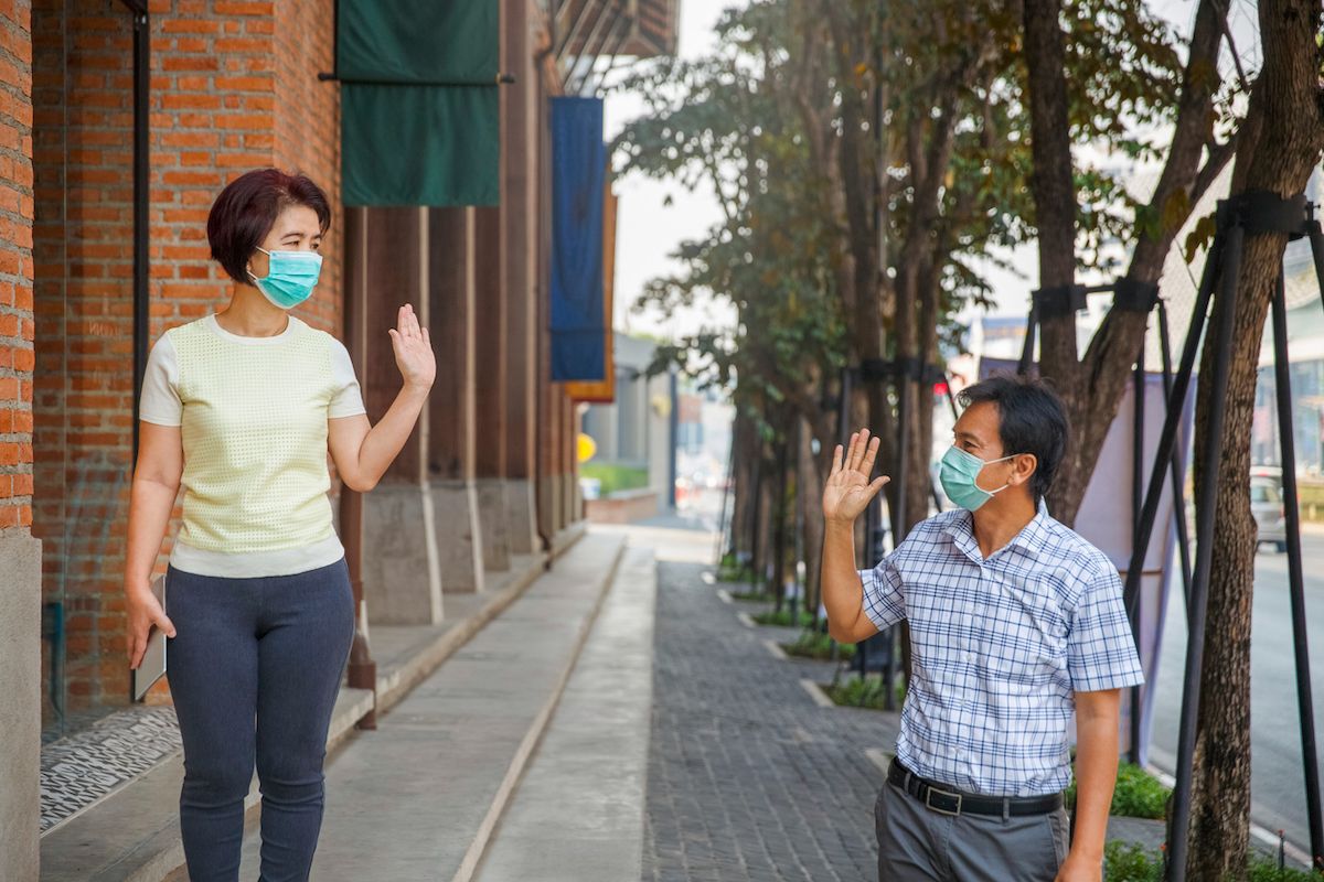 Le persone di mezza età asiatiche indossano maschere e mantengono le distanze sociali per evitare la diffusione di COVID-19