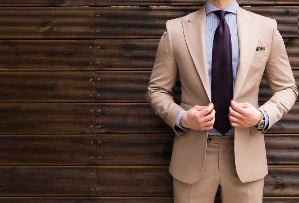 hombre vestido con un traje marrón y una corbata morada
