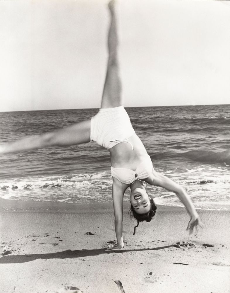 mulher na praia fazendo pirueta de biquíni na década de 1940