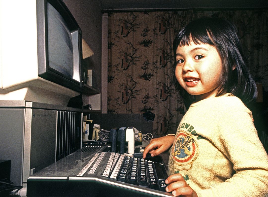 Trejų metų mergaitė žaidžia su TI 99 4a namų kompiuteriu, 1986 m., Kalifornija, JAV.