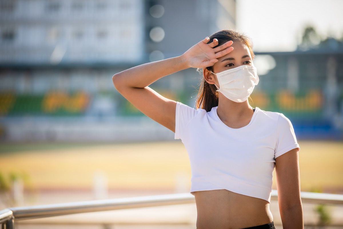femeia sport fitness se odihnește obosită și poartă o mască de protecție împotriva prafului și a poluării în oraș