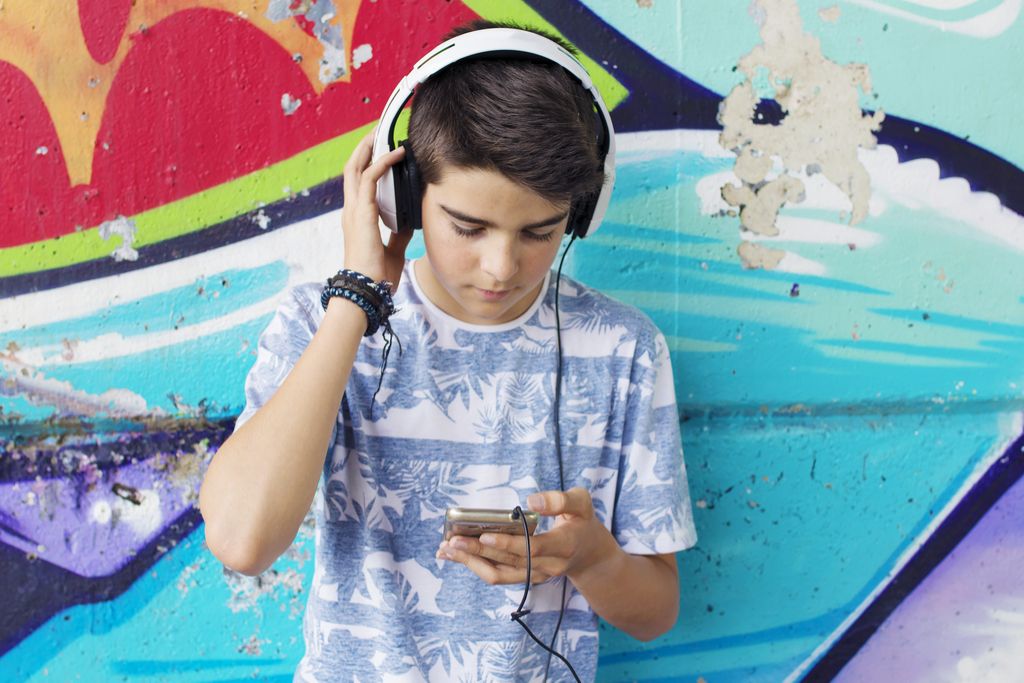 Teini-ikäinen kuulokkeilla tosiasioista, jotka saavat sinut onnelliseksi