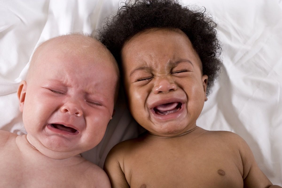 ansikter av hvit baby og svart baby som gråter