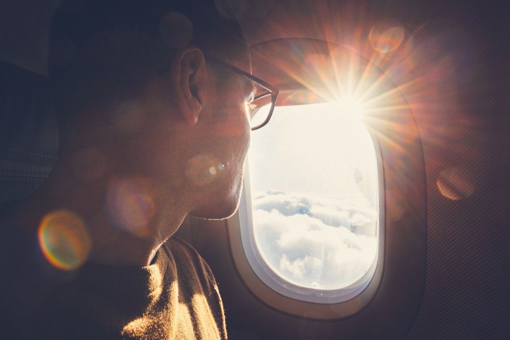 мъж, носещ очила, гледащ през прозореца на самолета