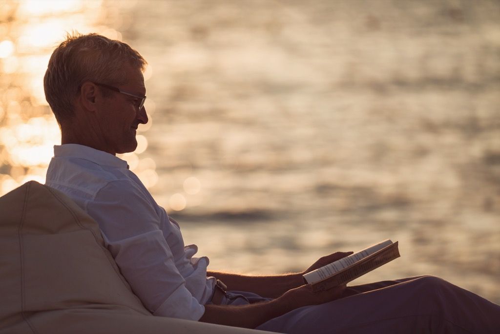 Mies lukee runoja meren rannalla