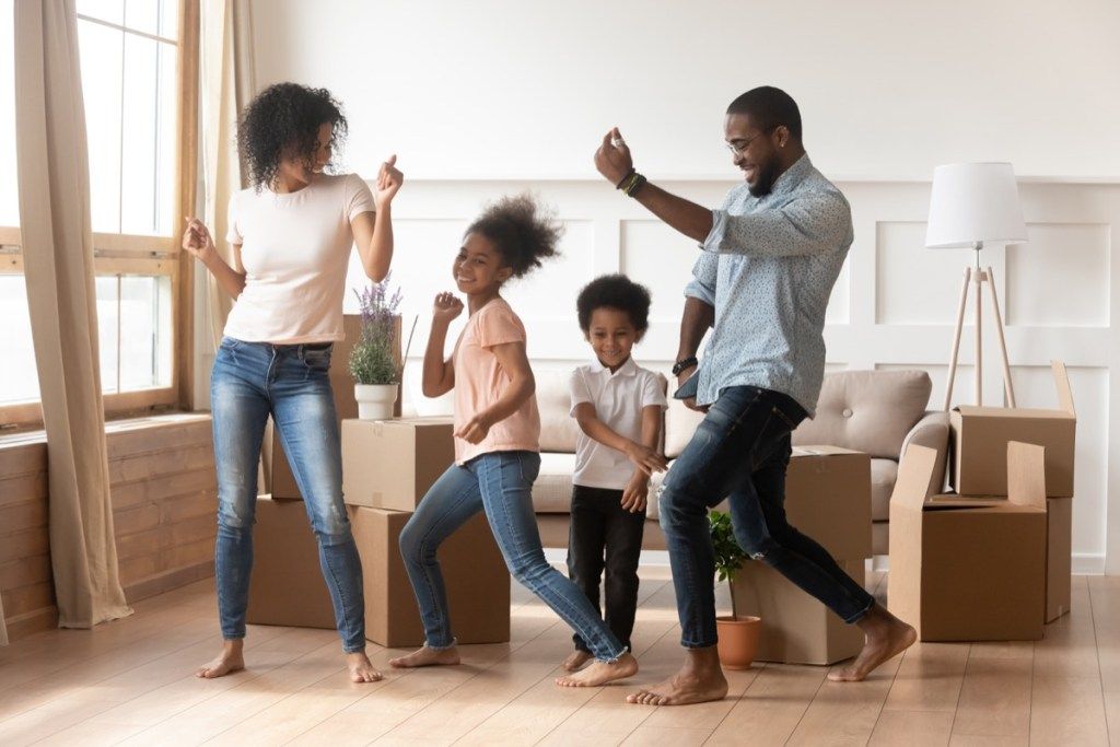 mladá černá rodina tančí v obývacím pokoji
