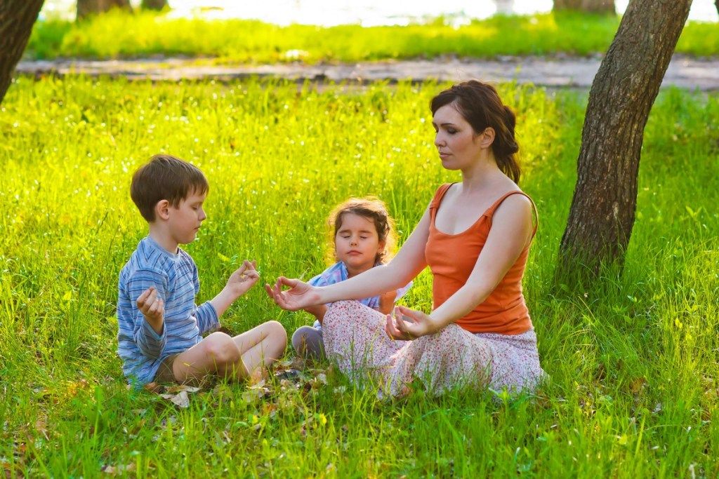 bílá matka a děti meditovat v trávě