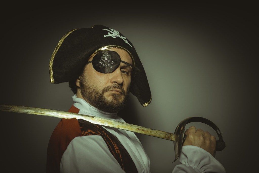 Hombre disfrazado de pirata con parche en el ojo y espada