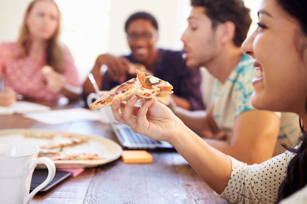 trabajadores de oficina comiendo pizza en una reunión
