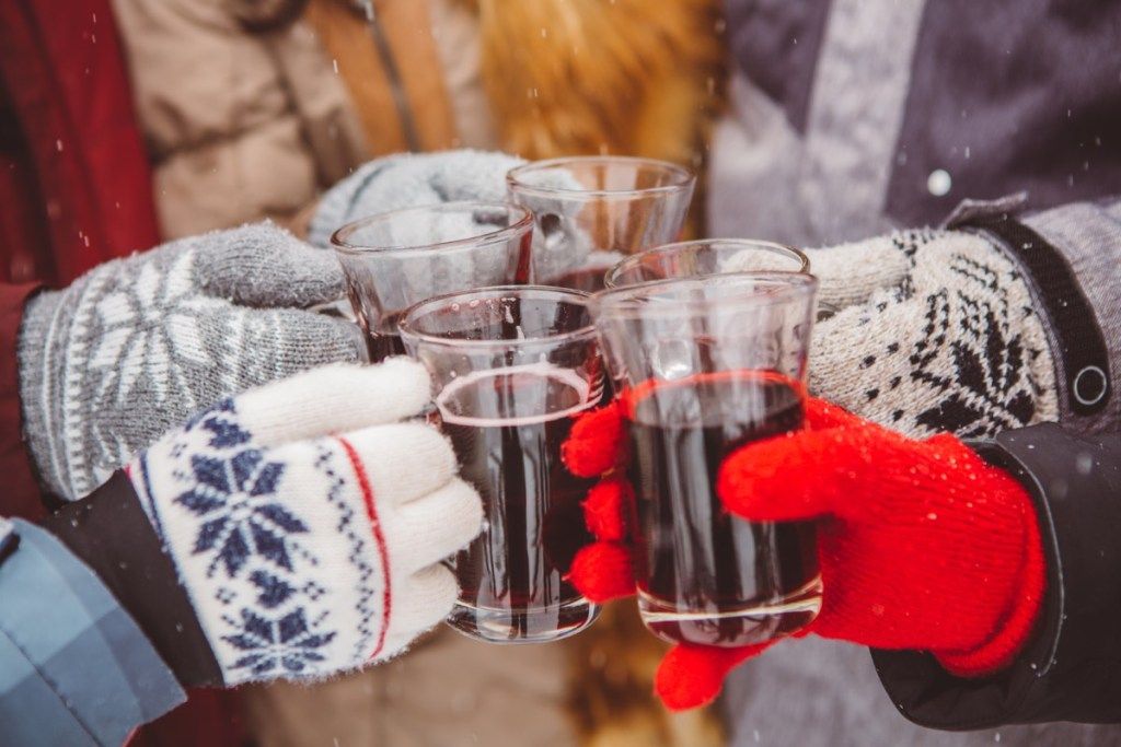 một nhóm bạn đeo găng tay mùa đông gõ vào ly rượu trong tiếng hoan hô