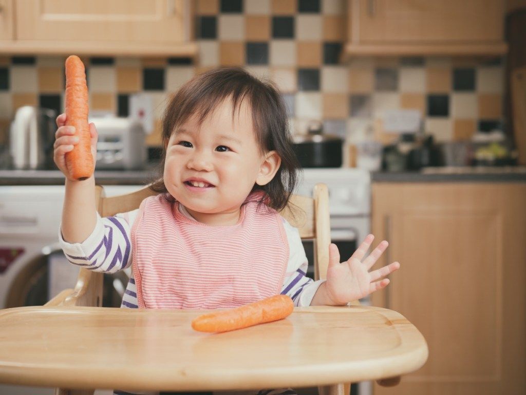 azijska beba koja drži mrkvu