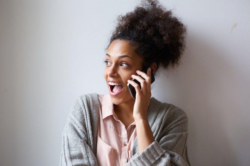 nainen nauraa puhelimessa