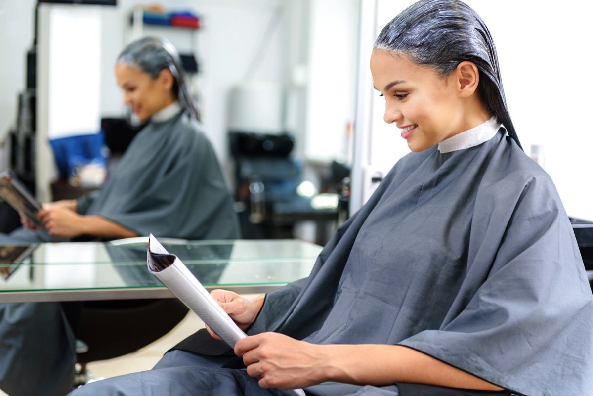 Wanita membaca majalah di salon rambut
