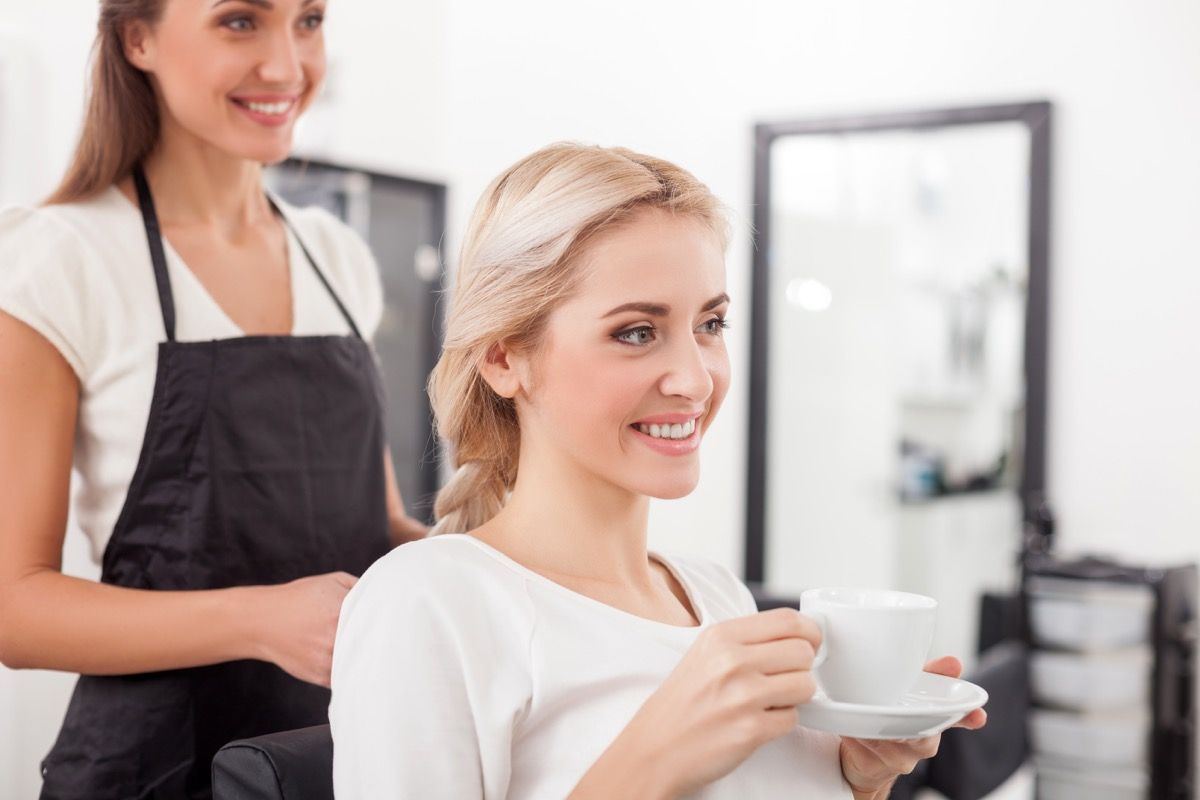 Kvinde, der har en kop te eller kaffe i frisørsalonen
