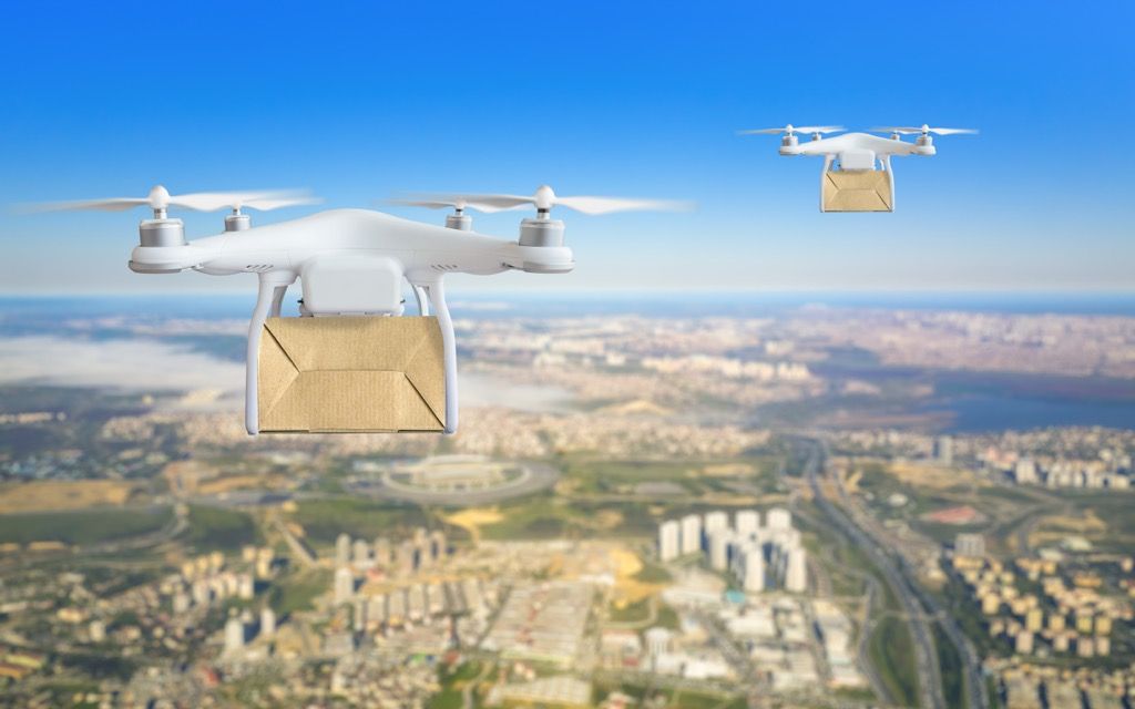 дронове, доставящи пакети в небето над градски пейзаж