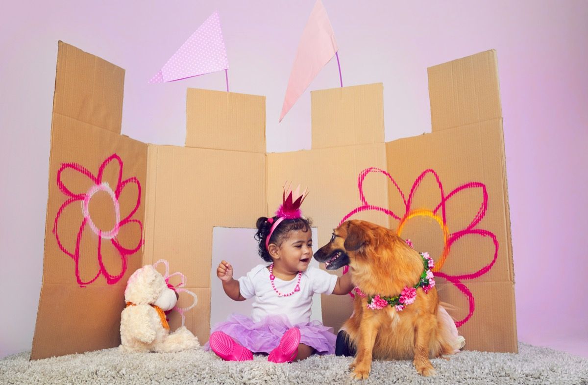 Väike tüdruk, kes mängib oma koeraga kleiti