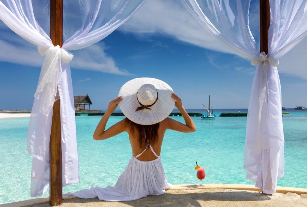 Mulher bonita com chapéu branco aproveita as férias de verão nos trópicos - imagem